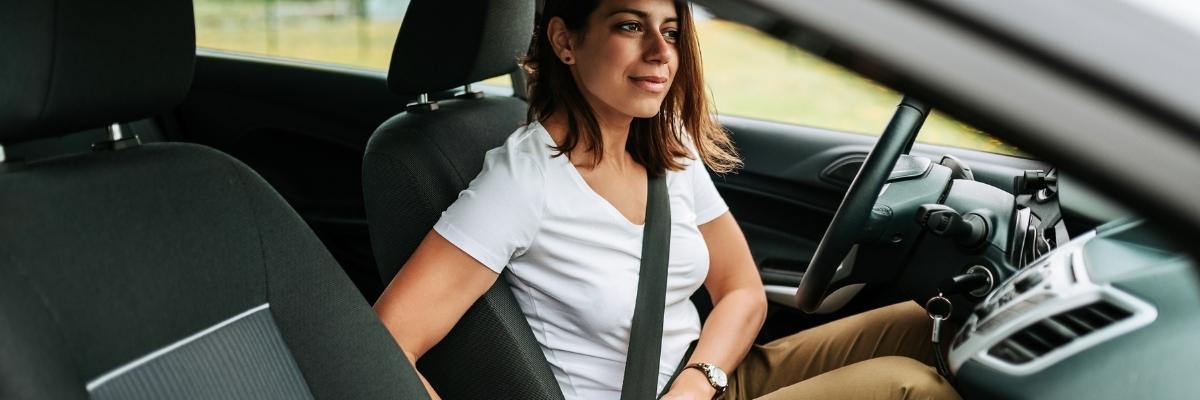 woman putting on seat belt on her own